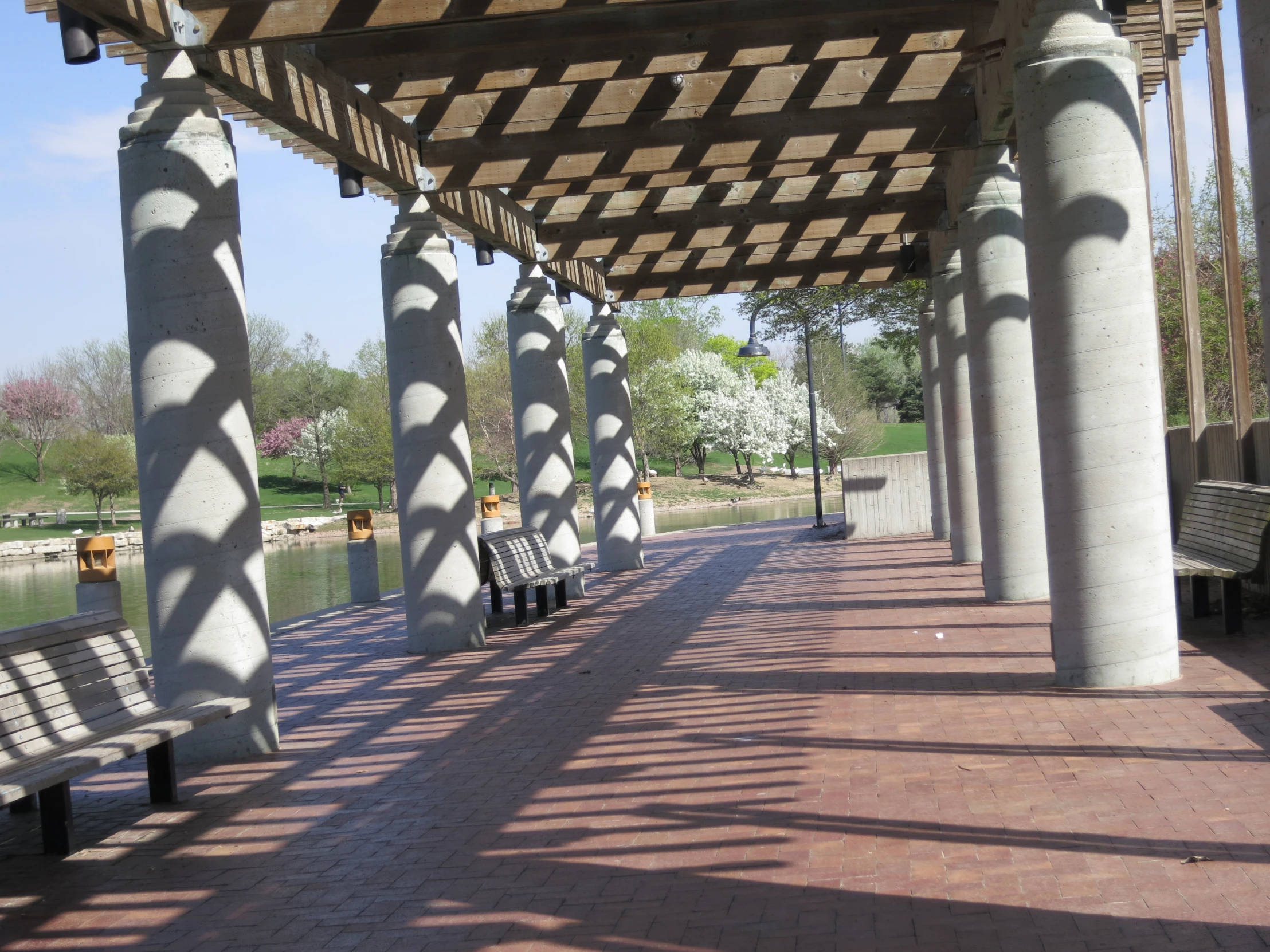 several benches along a wide lined with pillars and grass