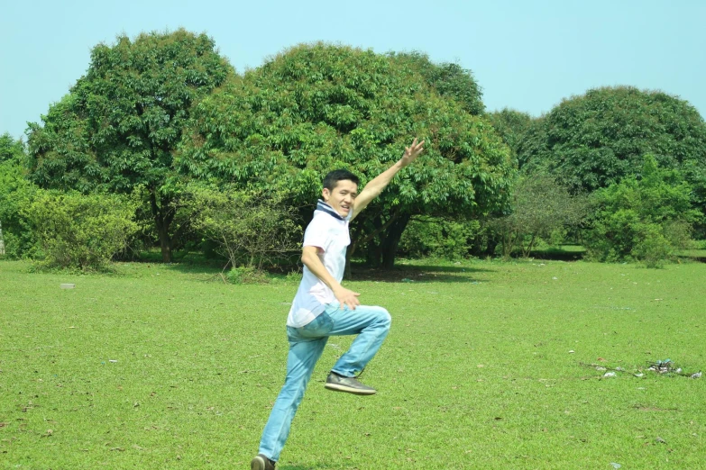 a man wearing blue jeans and a white shirt playing frisbee
