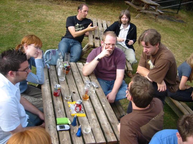 a group of people sitting around a wooden picnic table