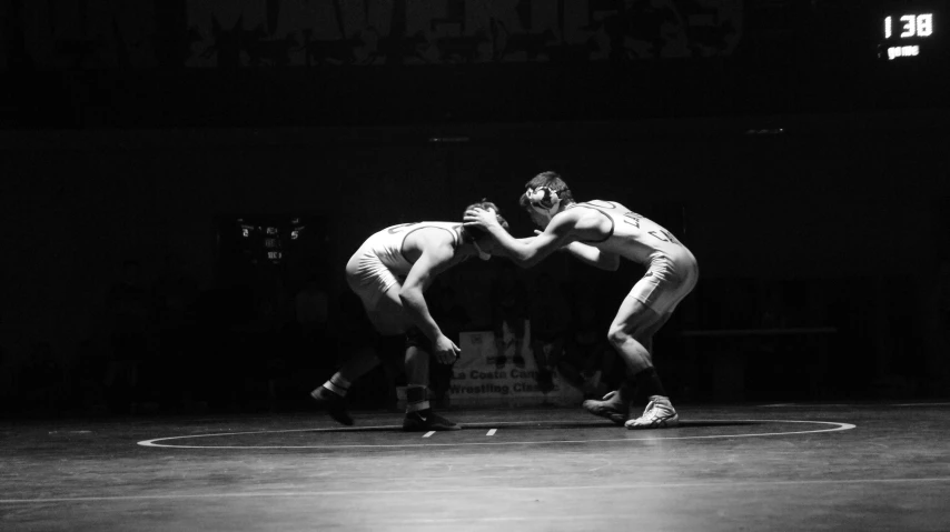 two wrestlers during a match one wrestler is bent over in the middle