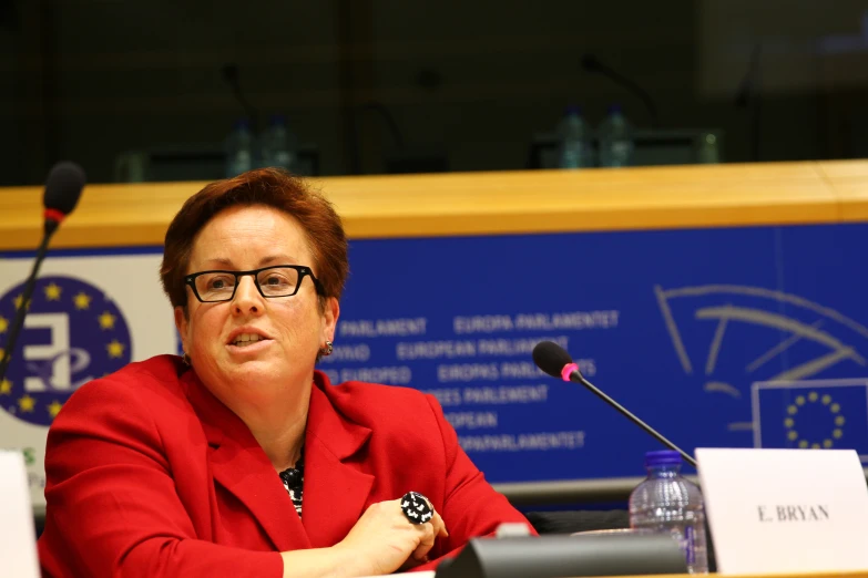 a woman sitting at a table in front of microphones