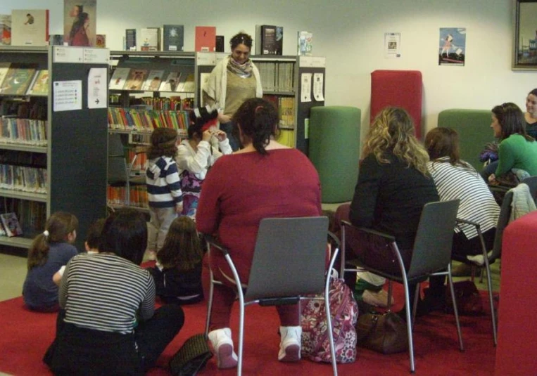 a group of children sitting on chairs and in front of bookshelves