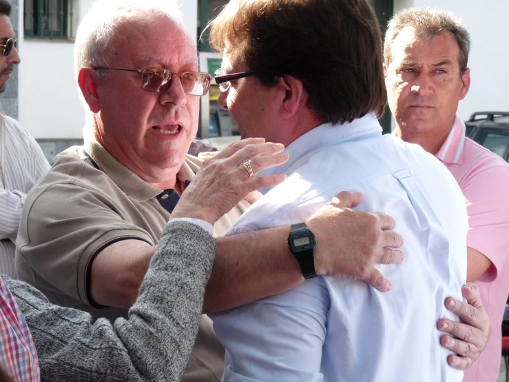 two men hug each other outside in front of a group of men