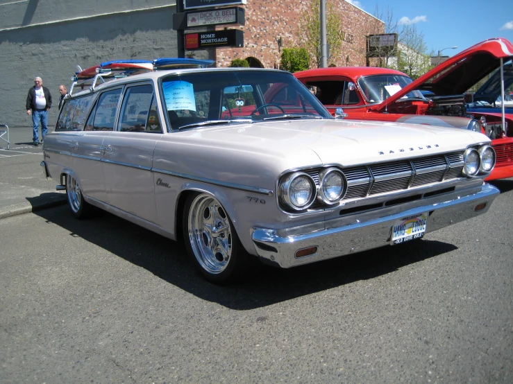 old car with surfboard rack parked on the side of the road