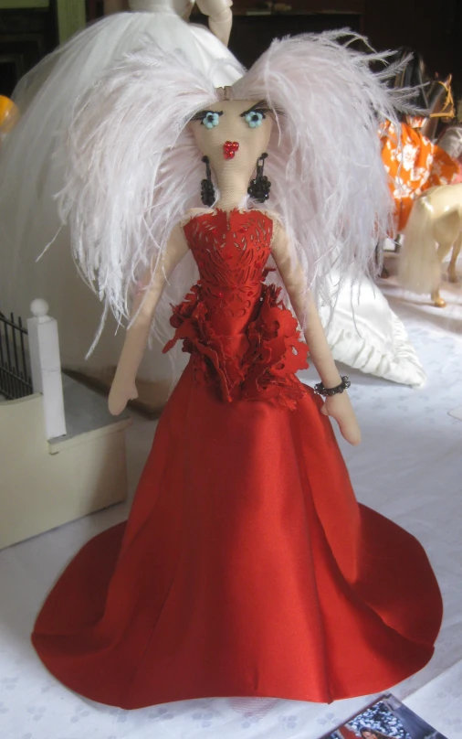 a red dress is sitting on a table with two dolls