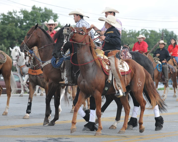 cowboys riding their horses in the street