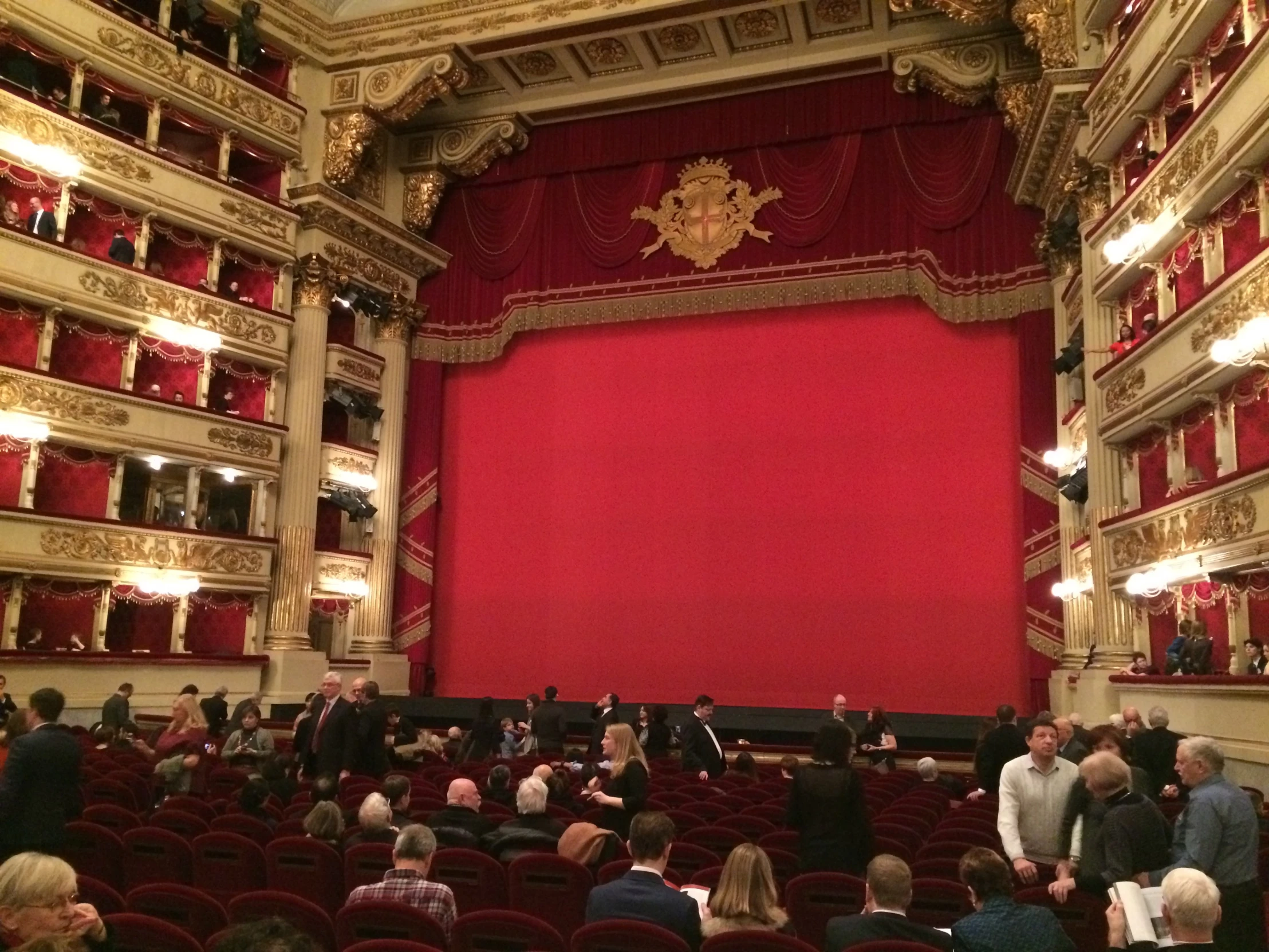 a red screen in a large auditorium with many people sitting around it