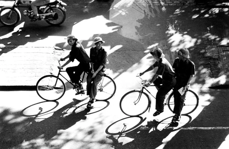 three men riding bicycles on a paved area