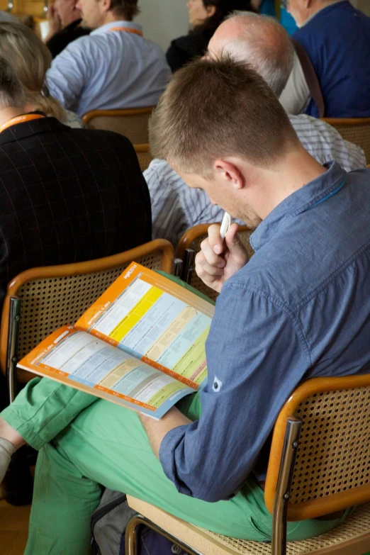 a man sits in a chair holding a folder