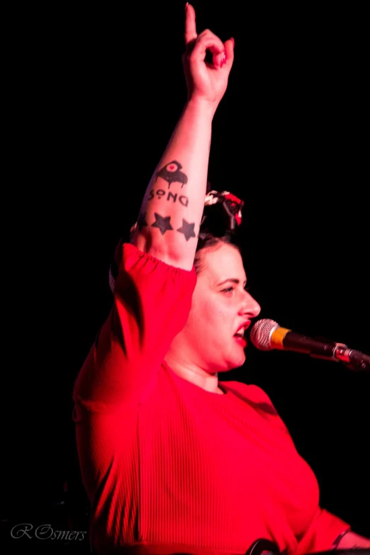 woman with tattooed arm and wrist reaching up in the air