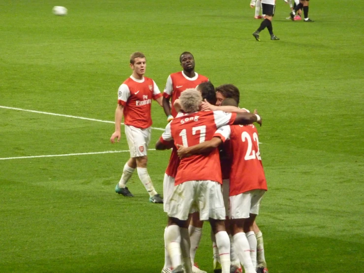 three men are huddled at the bottom of a soccer field