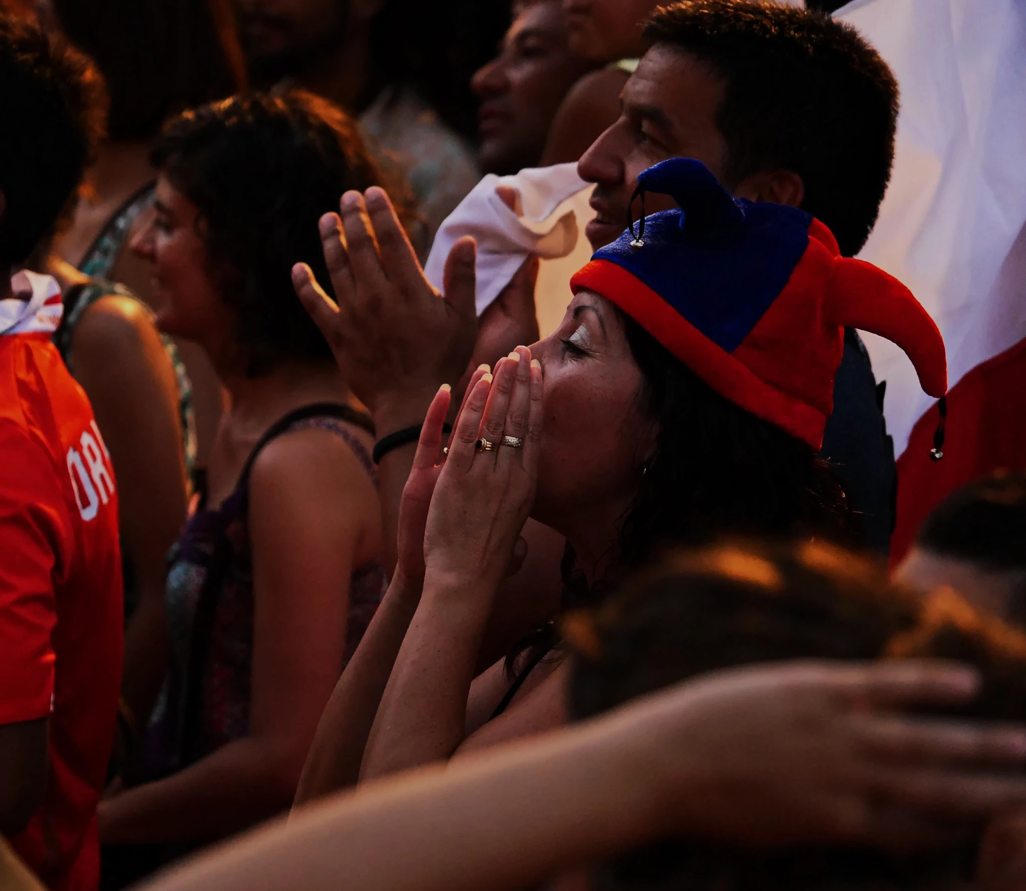 woman in large crowd rubbing her face under hands