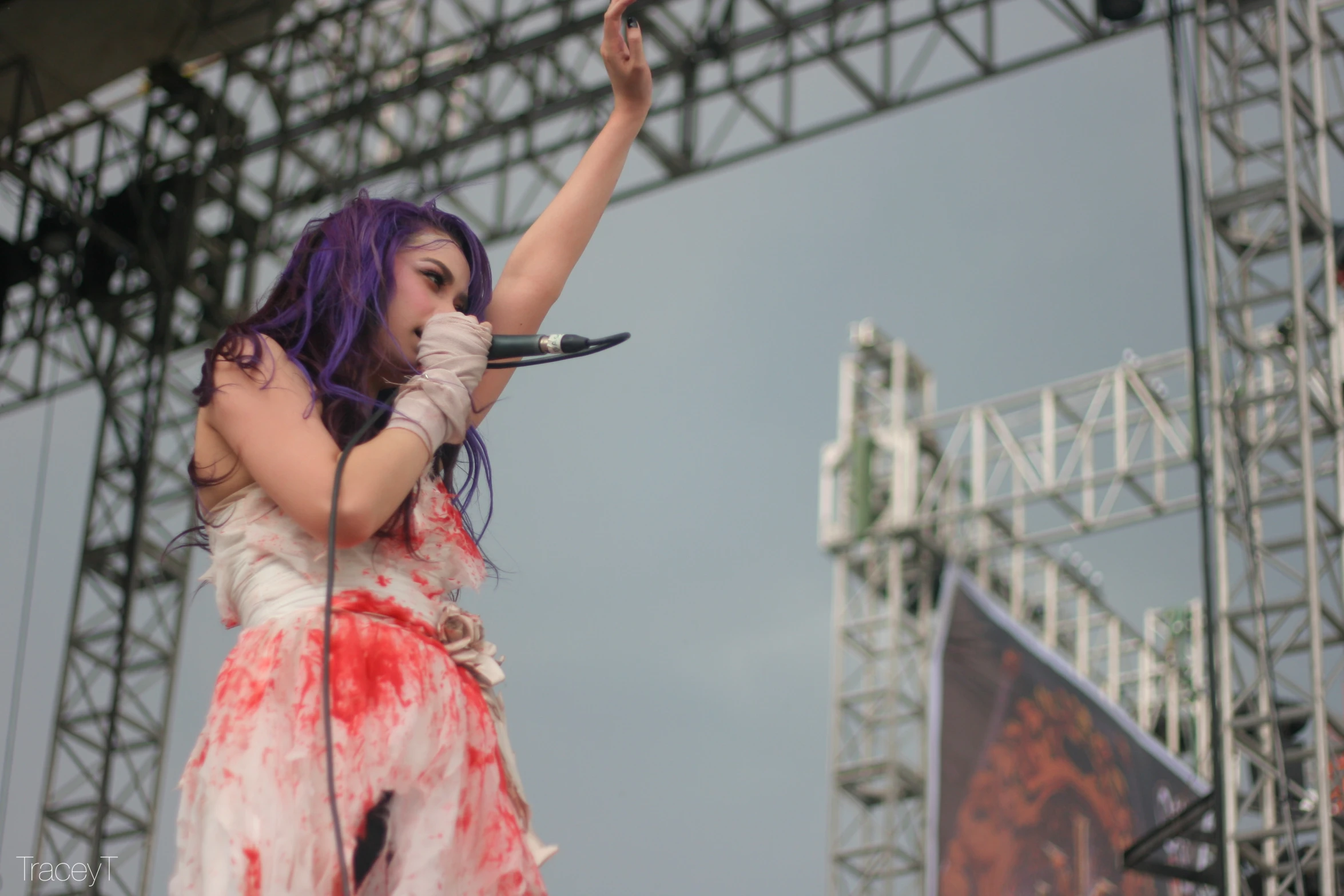 a woman with purple hair holding a microphone and standing up