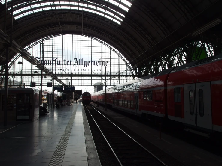 red and white train parked under a big, glass covered building