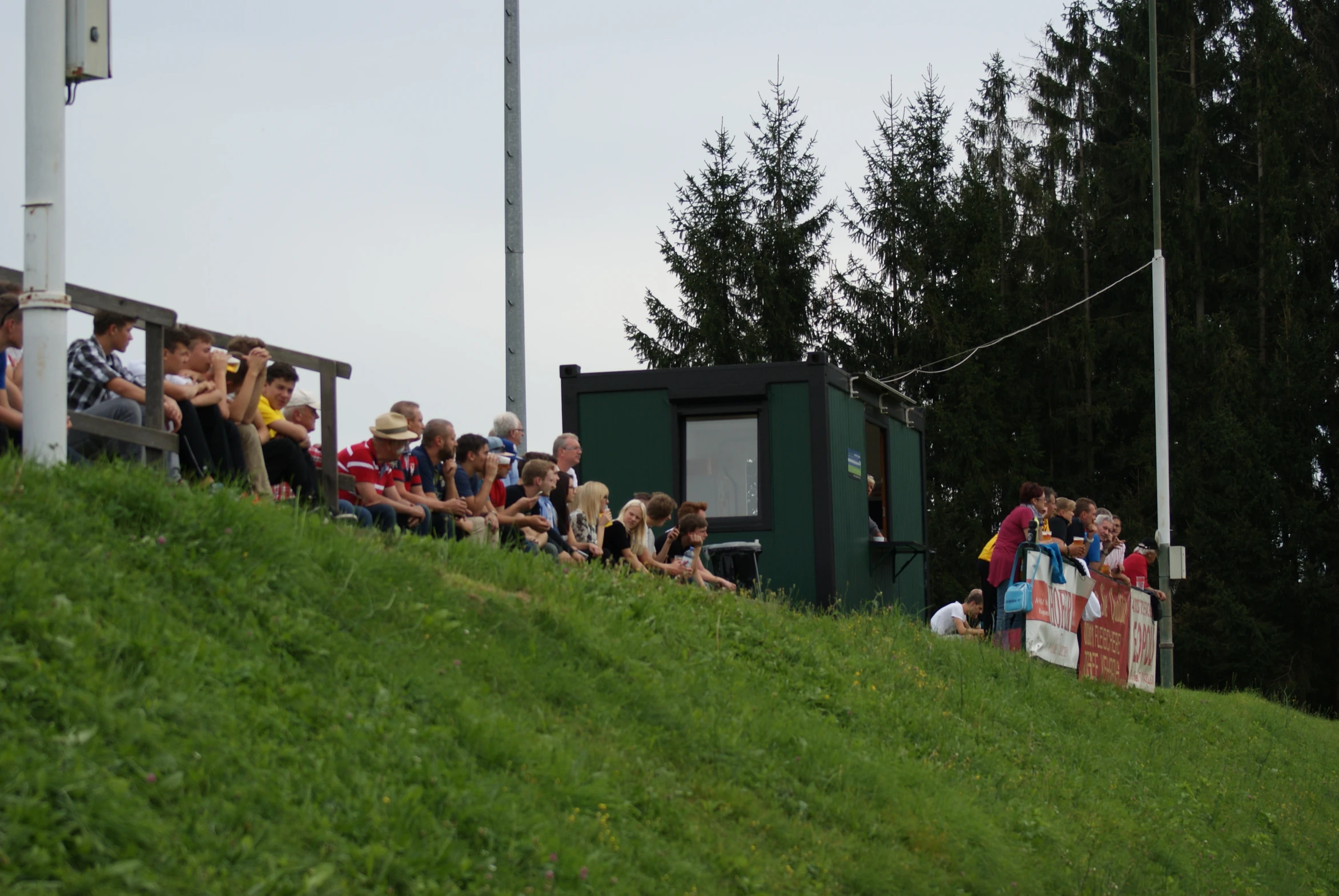 people sitting on bench near small structure in grassy field