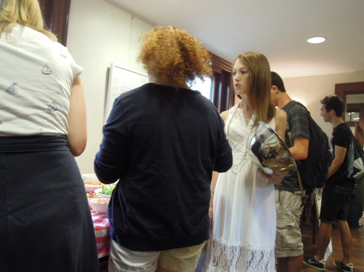 woman in white dress with red hair standing by a group of people