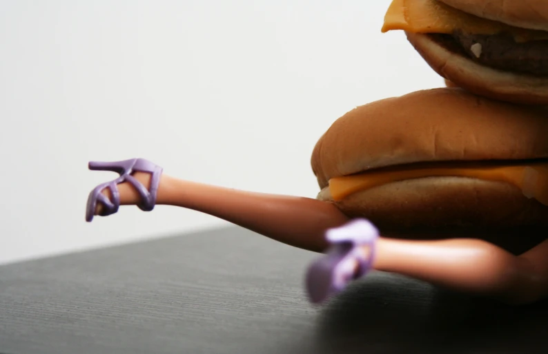 a doll's hand reaching toward a hamburger bun