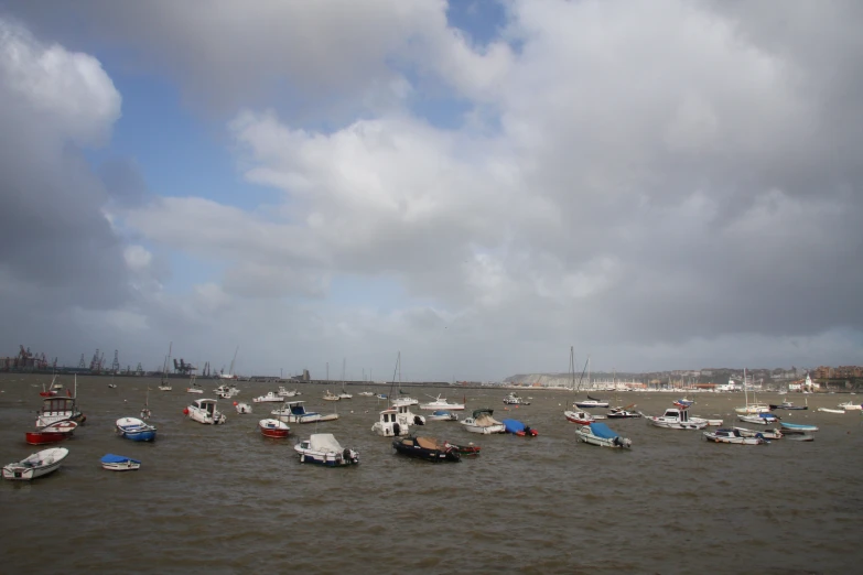 many boats floating in the water on a cloudy day