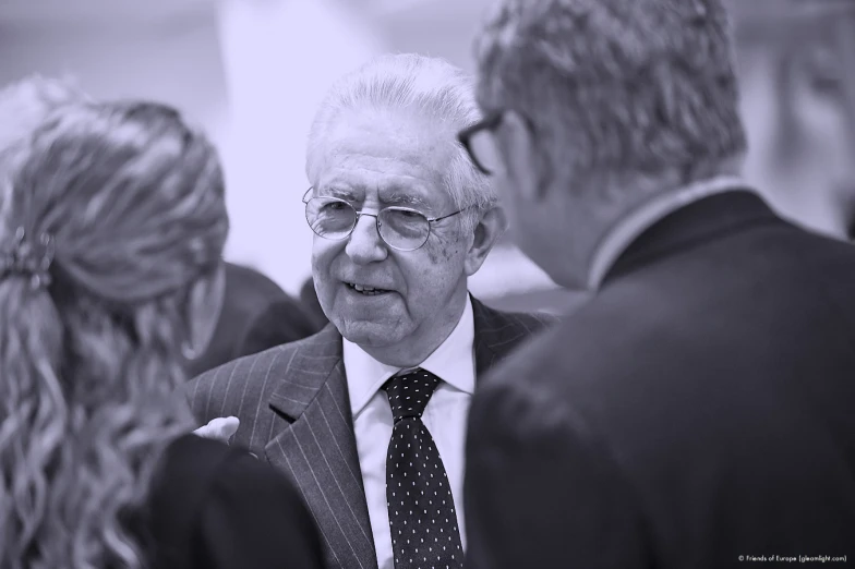 a man with a suit and tie talking to two women