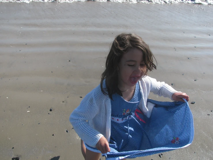 little girl playing on the beach in her blue and white clothing