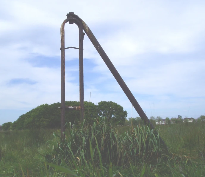 a large metal pipe is standing in tall grass