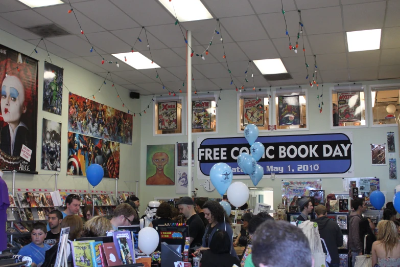 a group of people in a book store next to a bunch of blue and white balloons