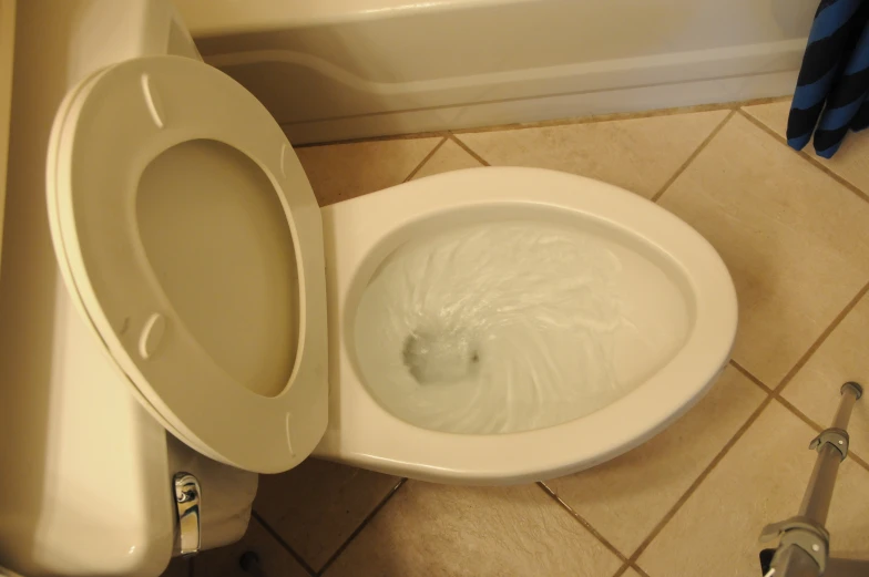 a toilet bowl filled with white liquid sitting on a tiled floor