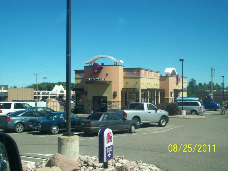 a store with cars parked outside and people walking around