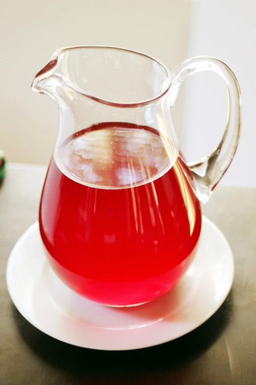 a glass jug filled with red liquid sits on a plate