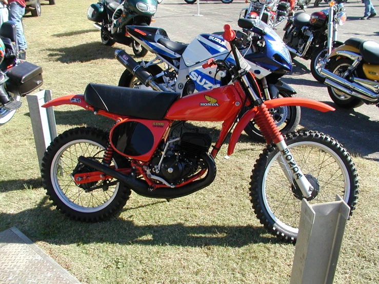 a red dirt bike parked next to other motorcycles on display