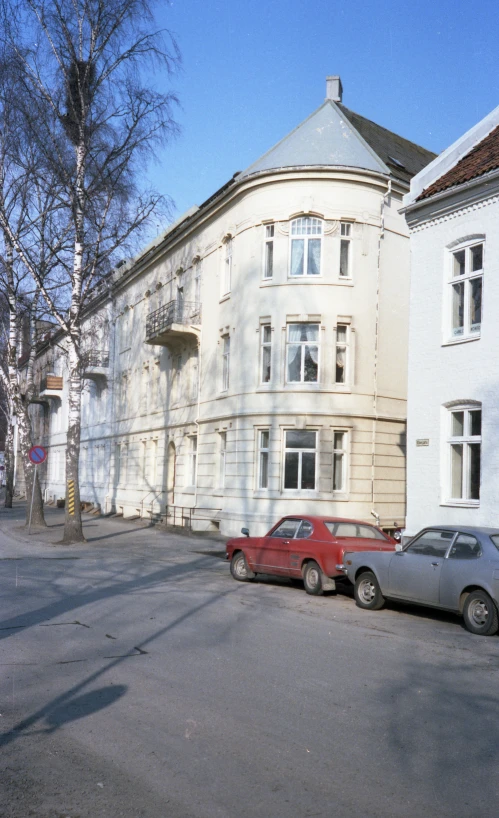 two cars parked on the street side by a large white building