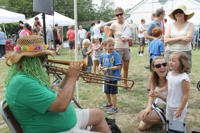 a man with a green wig plays trumpet to a group of people