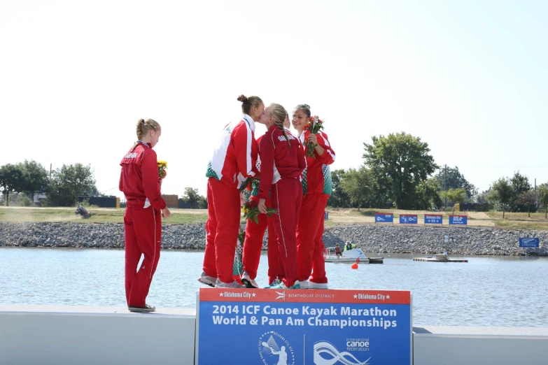 olympic performers stand on a podium next to a lake