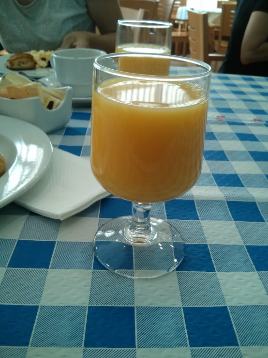 an orange cocktail in a wine glass on a table