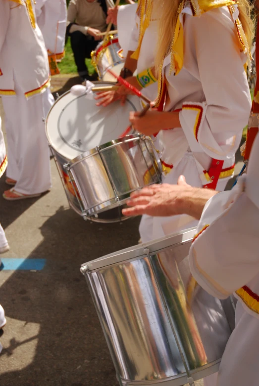 some people are dressed in marching uniforms playing steel drums
