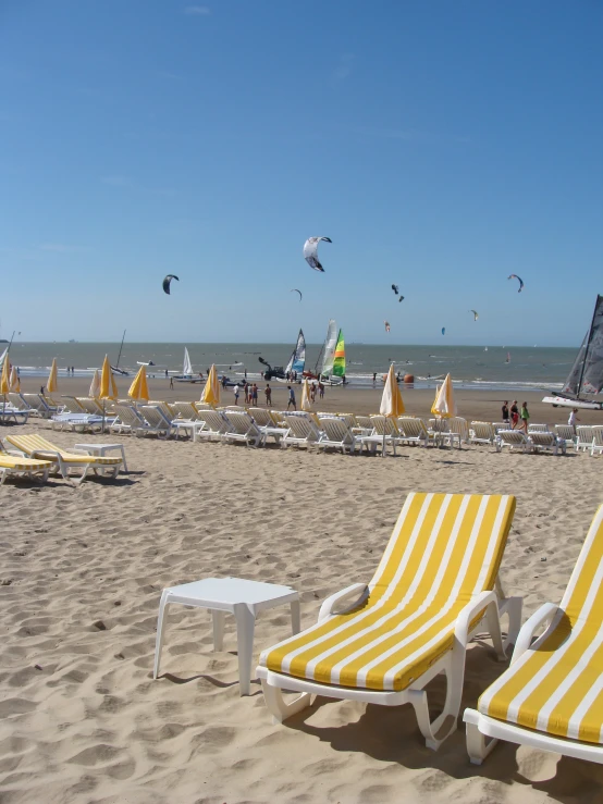 yellow and white striped chairs sitting on a sandy beach