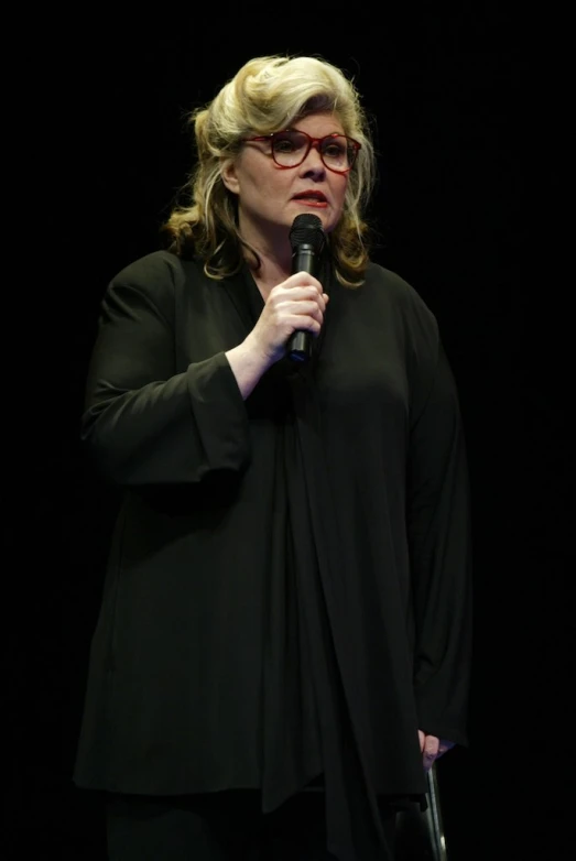 a woman wearing black holding a microphone in her hand
