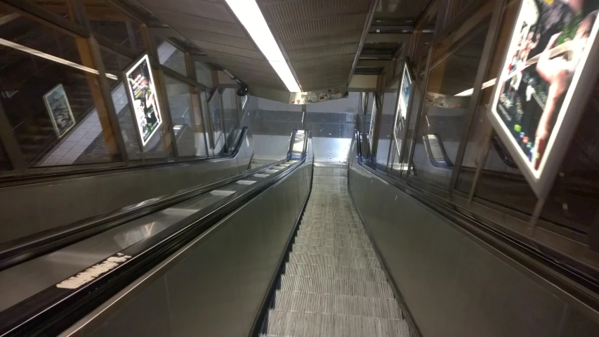 an empty escalator at a subway station with a person standing next to it