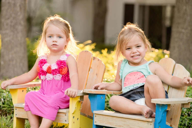 two little girls sitting in chairs outside