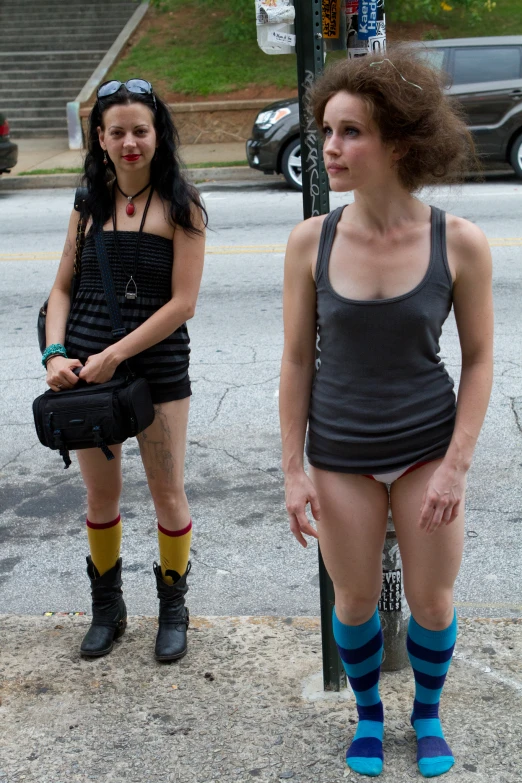 two women standing in front of a sign and a traffic pole