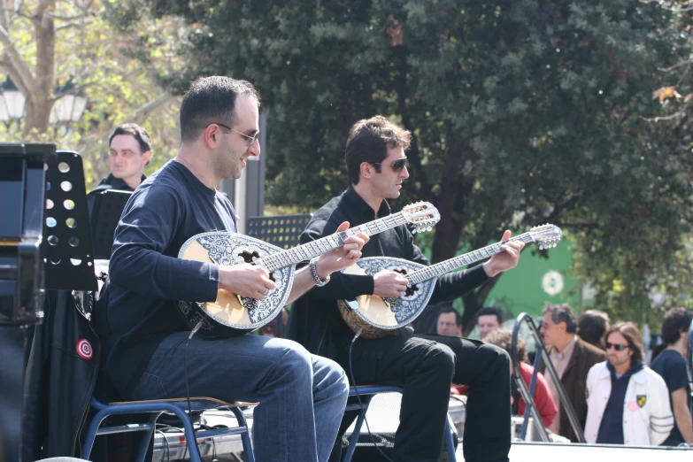 two young men sitting down with guitars in hand