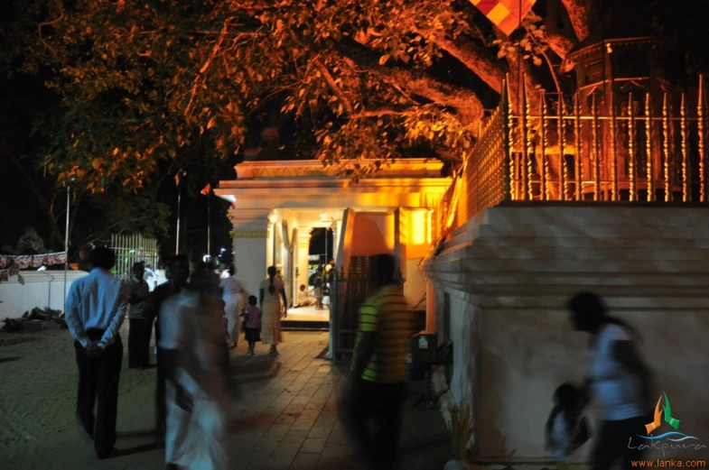 many people walking around at night by a building