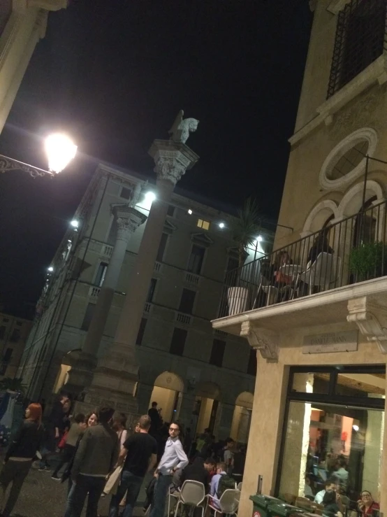 many people standing outside of a building by lights