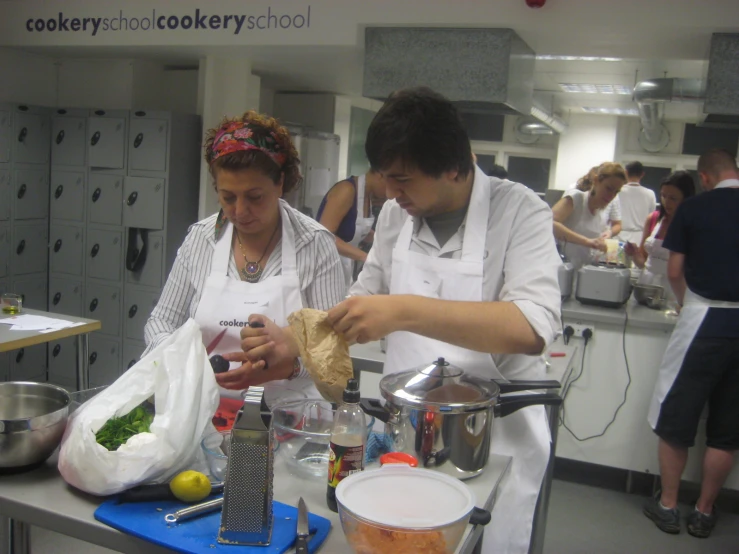 a woman and a man with aprons are cooking in a kitchen