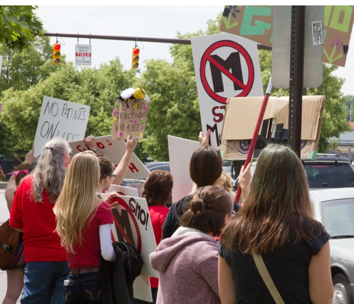 several protesters holding signs on a street corner