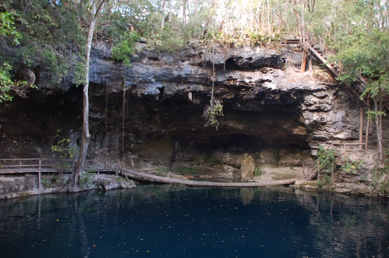 a large pool is surrounded by trees and a rocky cliff