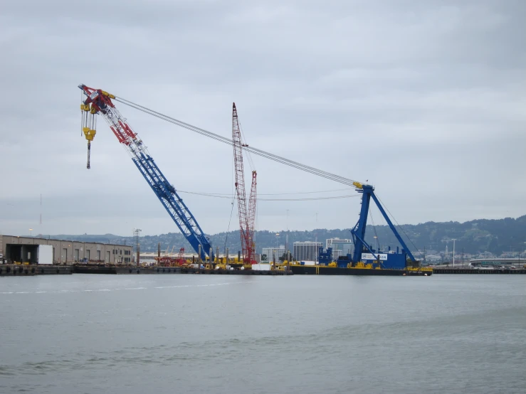 cranes on the water in front of a construction site