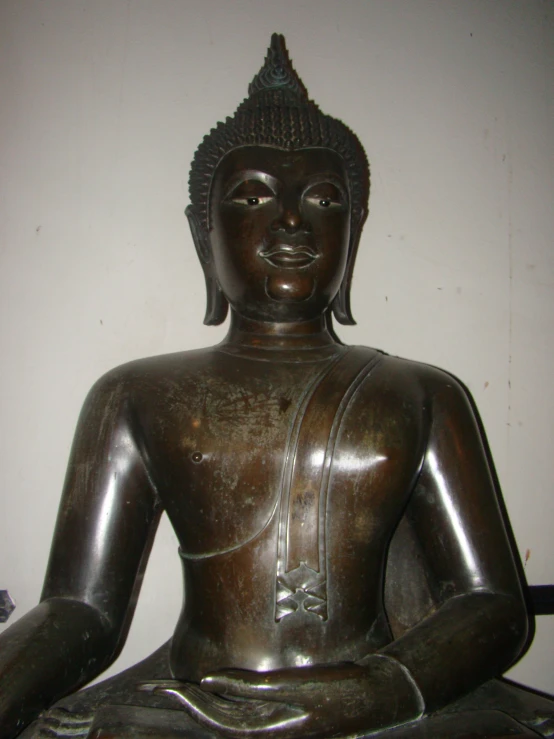 a bronze statue sits in front of the wall
