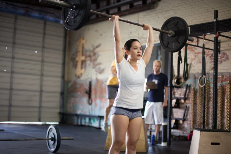 there is a woman lifting the barbell in a crossfit