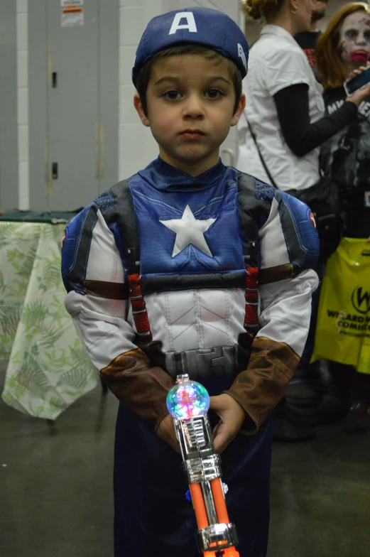 a little boy dressed as a captain america costume and holding his toy machine